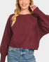 Woman wearing a burgundy sweater and blue jeans on a white background