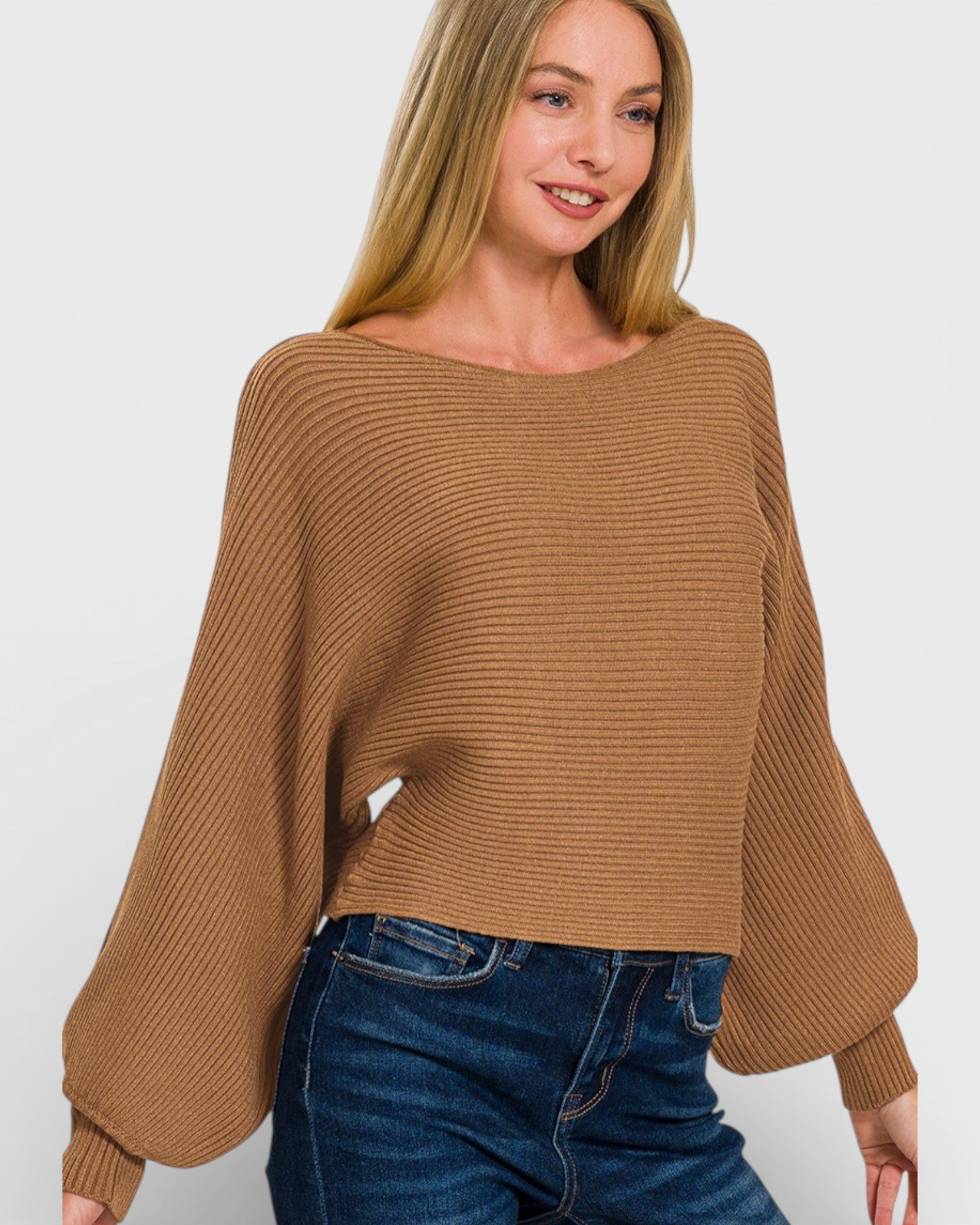 Woman wearing a brown sweater and blue jeans against a white background