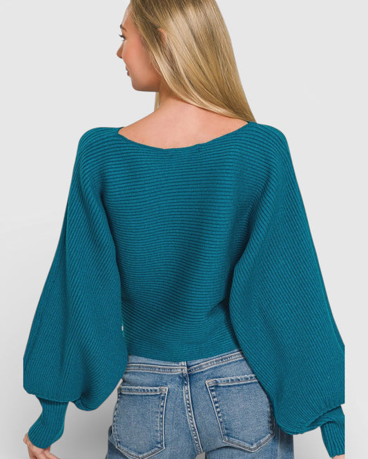 Person wearing a teal sweater with balloon sleeves on a plain background