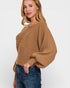 Woman wearing a brown sweater and blue jeans on a white background