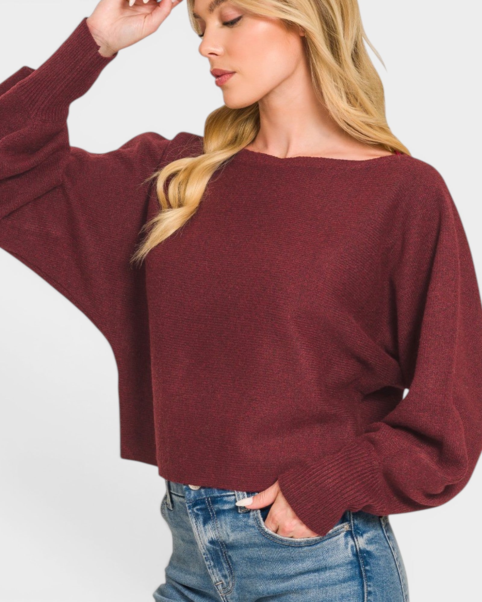 Woman wearing a burgundy sweater and blue jeans on a white background