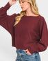 Woman wearing a burgundy sweater and blue jeans on a white background