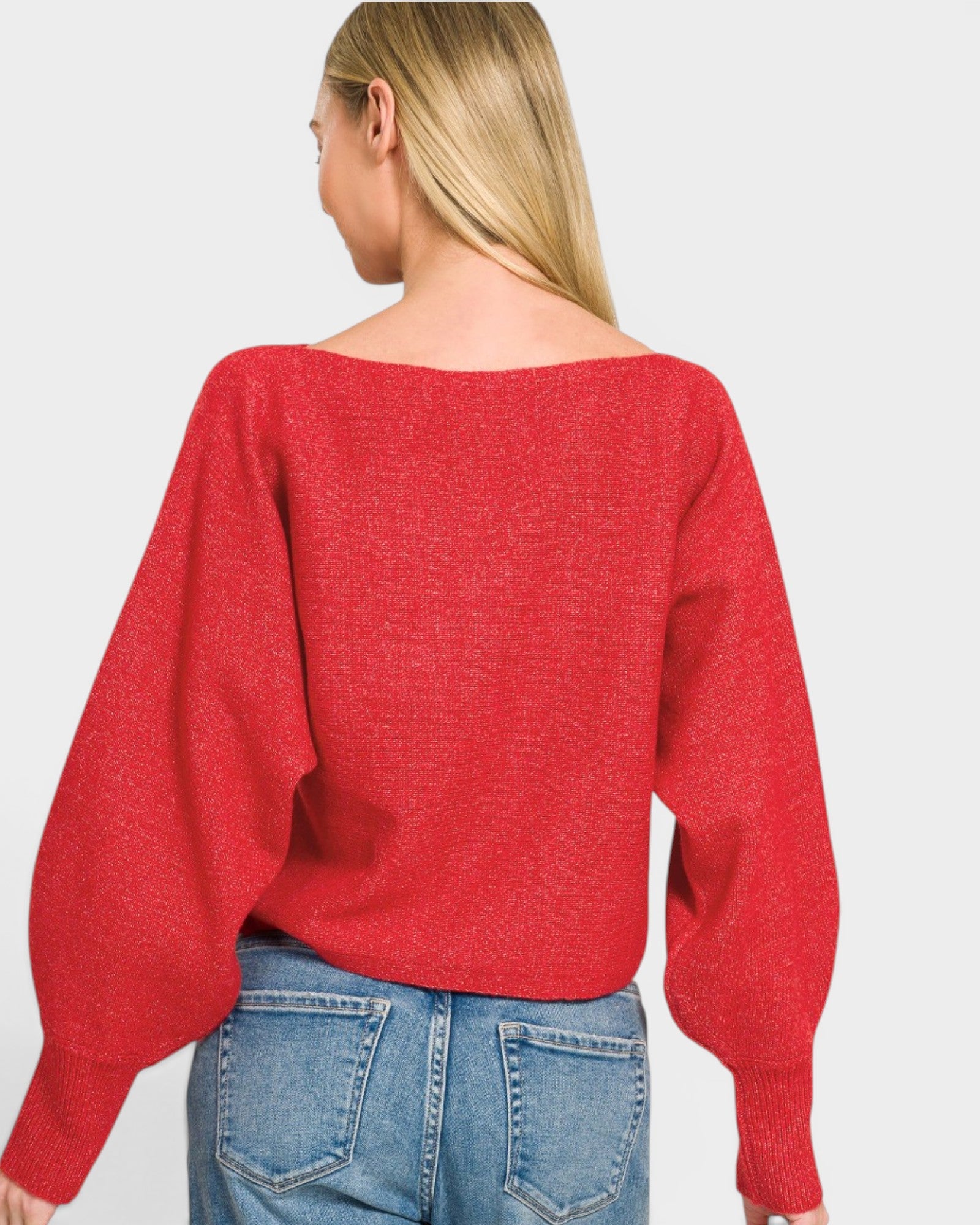 Person wearing a red sweater and blue jeans on a plain background