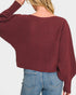 Person wearing a burgundy sweater and blue jeans on a plain background
