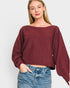 Woman wearing a burgundy sweater and blue jeans on a white background