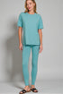 Woman wearing a teal outfit on a plain background