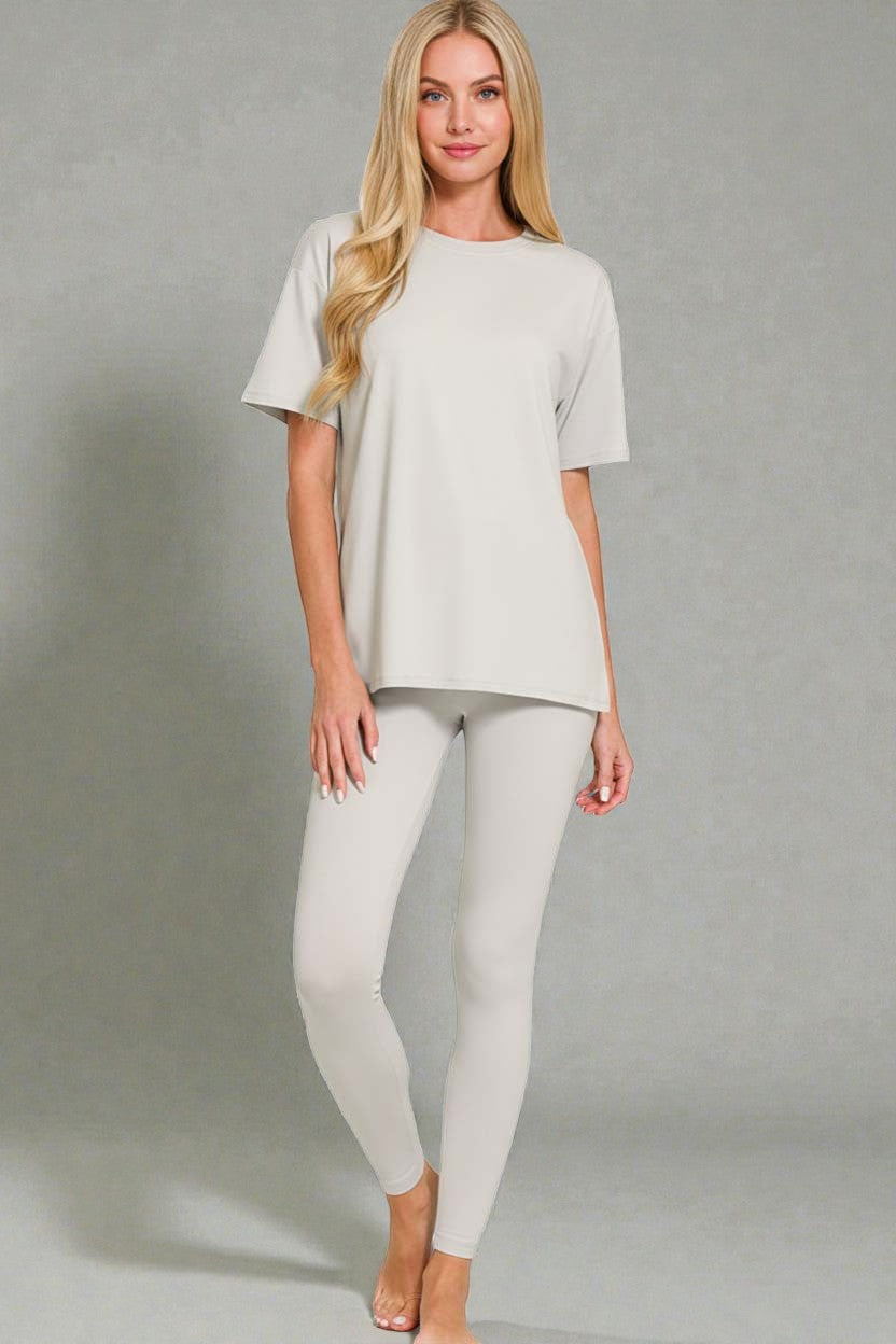 Woman wearing a light gray t-shirt and leggings against a plain background