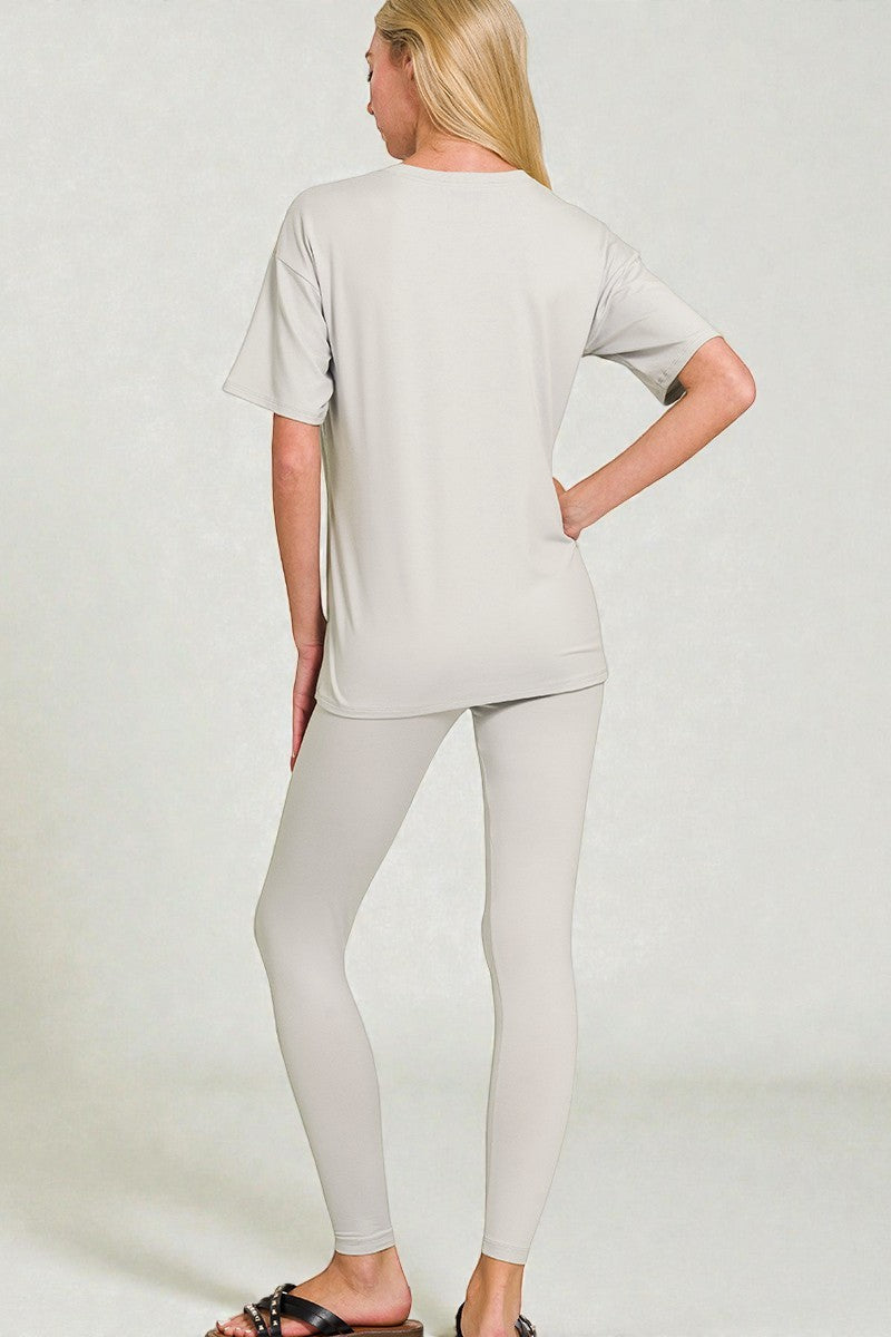 Woman wearing a light gray t-shirt and leggings on a white background