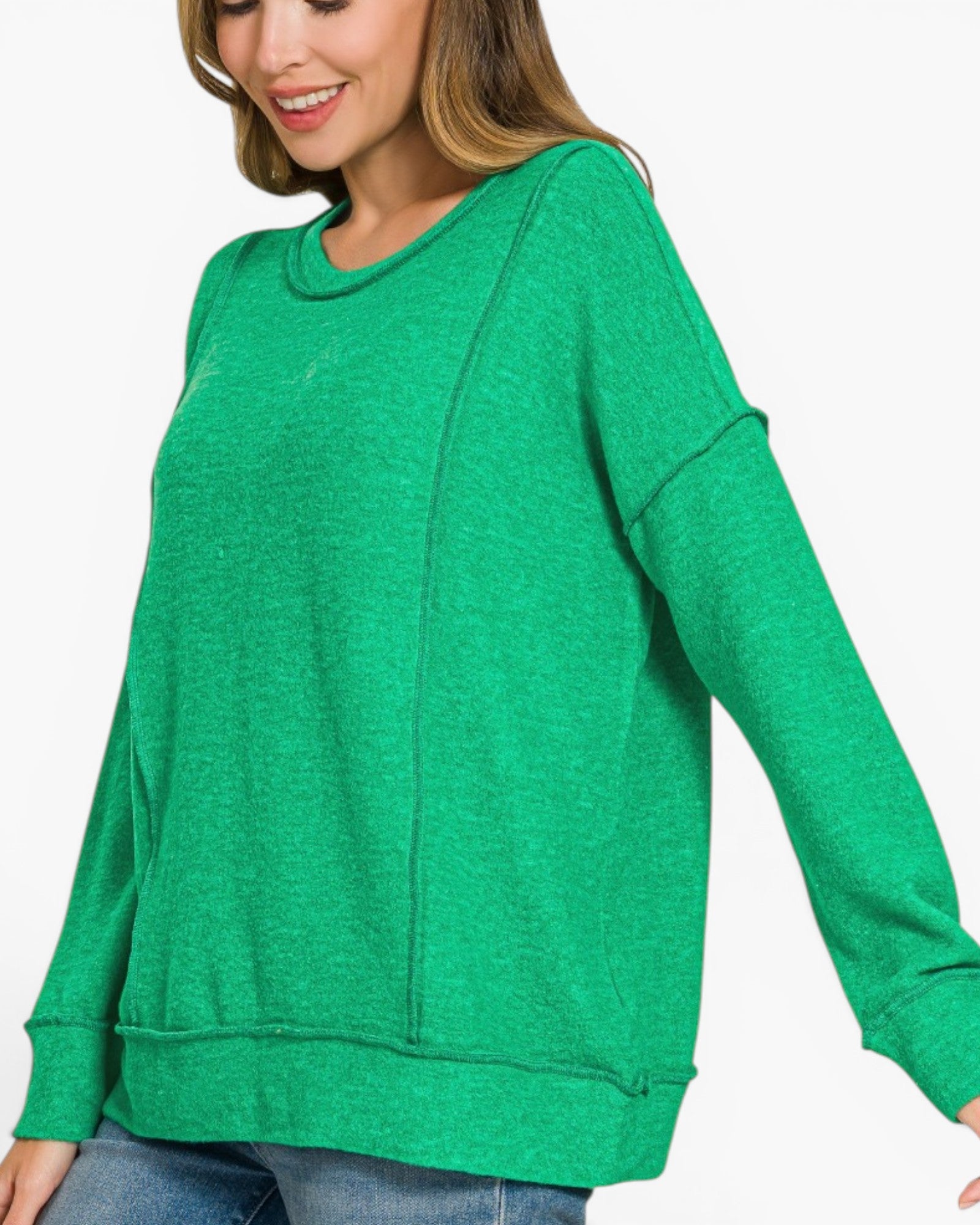 A woman wearing a bright green heathered crewneck sweatshirt with long sleeves and ribbed cuffs, paired with blue jeans, shown against a plain white background.