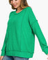 A woman wearing a bright green heathered crewneck sweatshirt with long sleeves and ribbed cuffs, paired with blue jeans, shown against a plain white background.