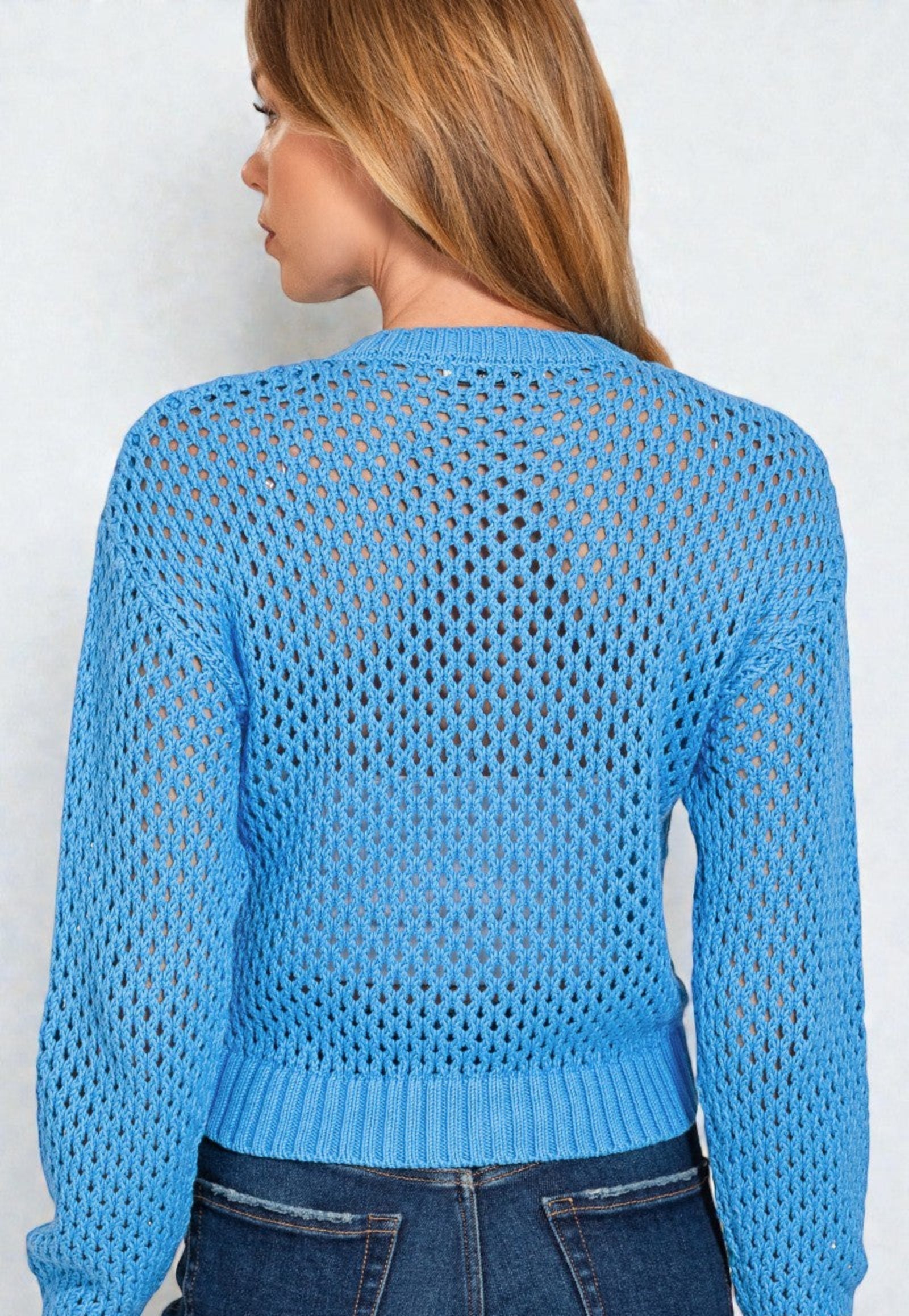 Woman wearing a blue open-knit sweater against a white background