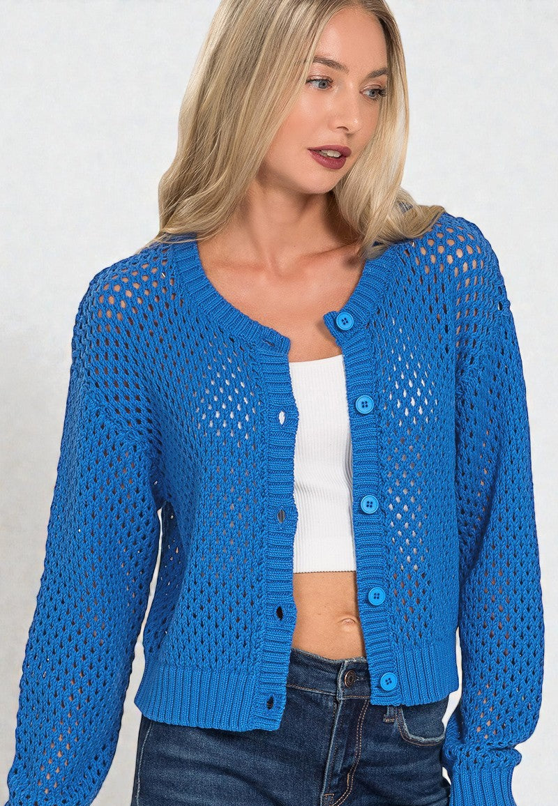 Woman wearing a blue knitted cardigan over a white top and jeans on a plain background