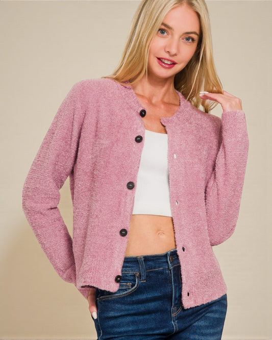 Woman wearing a pink cardigan with black buttons on a beige background