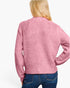 A woman viewed from the back wearing a heathered pink knit sweater and blue jeans against a plain white studio background.