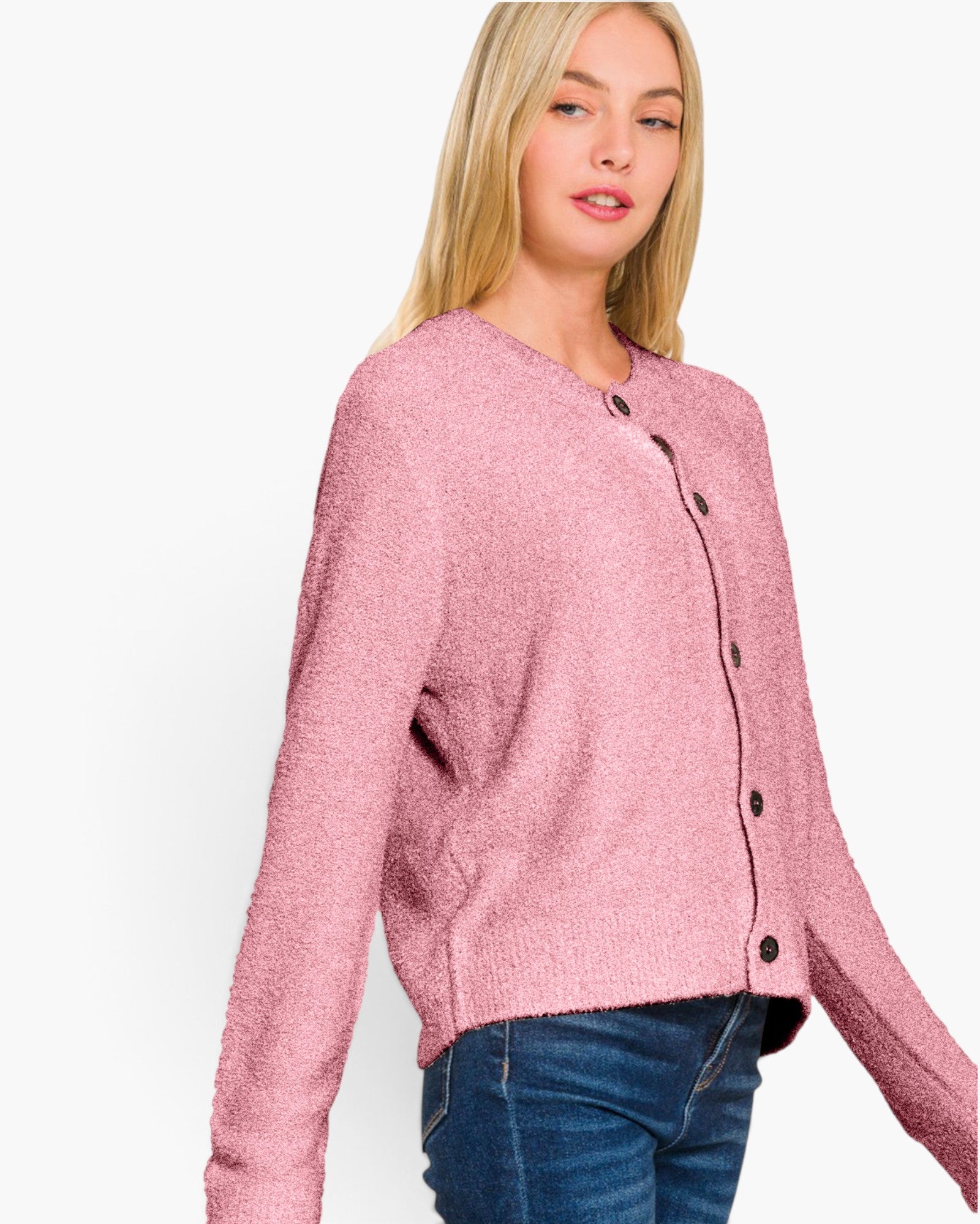A woman wearing a textured, fuzzy pink button-up cardigan sweater and blue jeans, photographed against a clean white studio background.