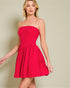 Woman wearing a strapless red dress against a beige background