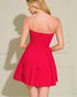 Woman wearing a strapless red dress against a neutral background