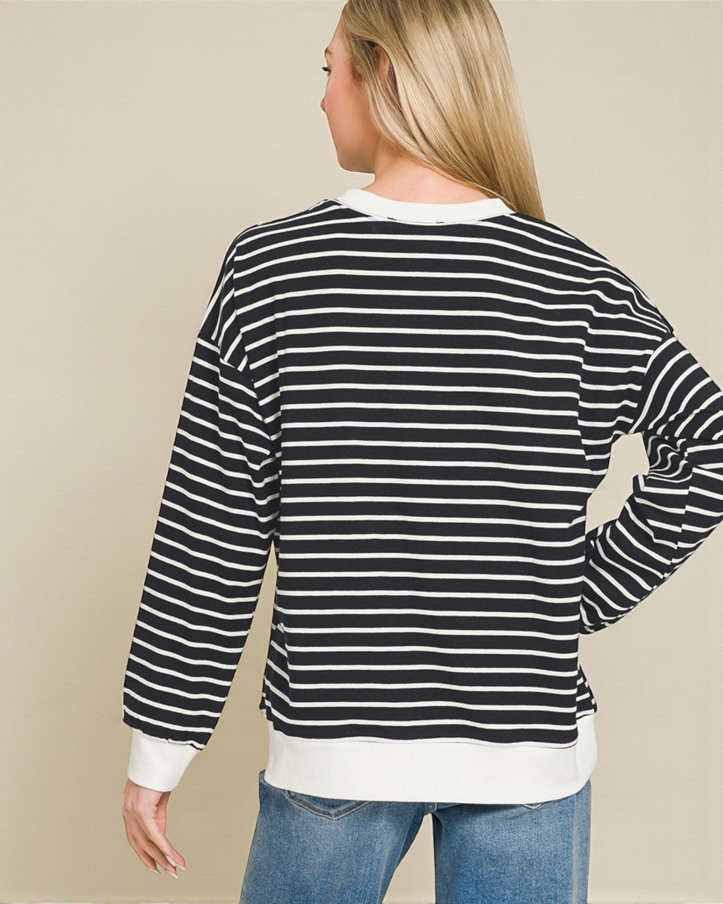 Person wearing a black and white striped sweater with a beige background