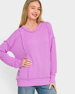 Woman wearing a purple sweater on a plain background