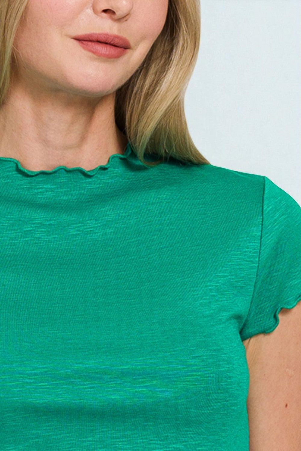 Close-up of a person wearing a green top with a plain background