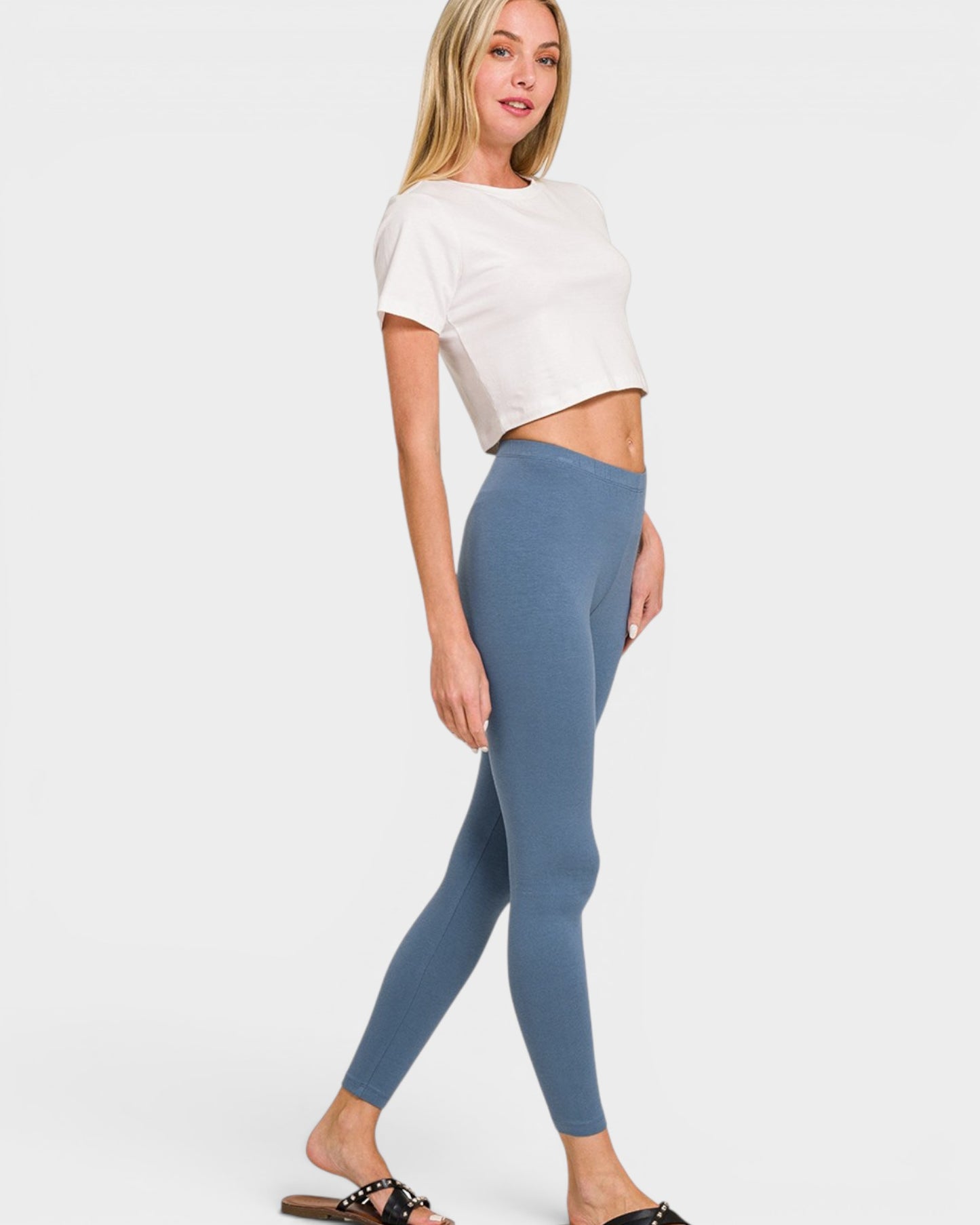 Woman wearing a white top and blue leggings on a white background