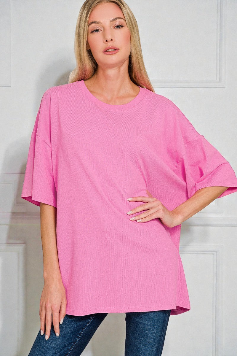 Woman wearing a pink oversized top and blue jeans against a white background