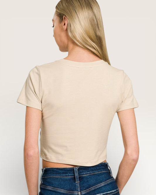 Person wearing a beige crop top and blue jeans on a plain background