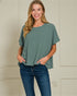 Woman wearing a green top and blue jeans against a plain background