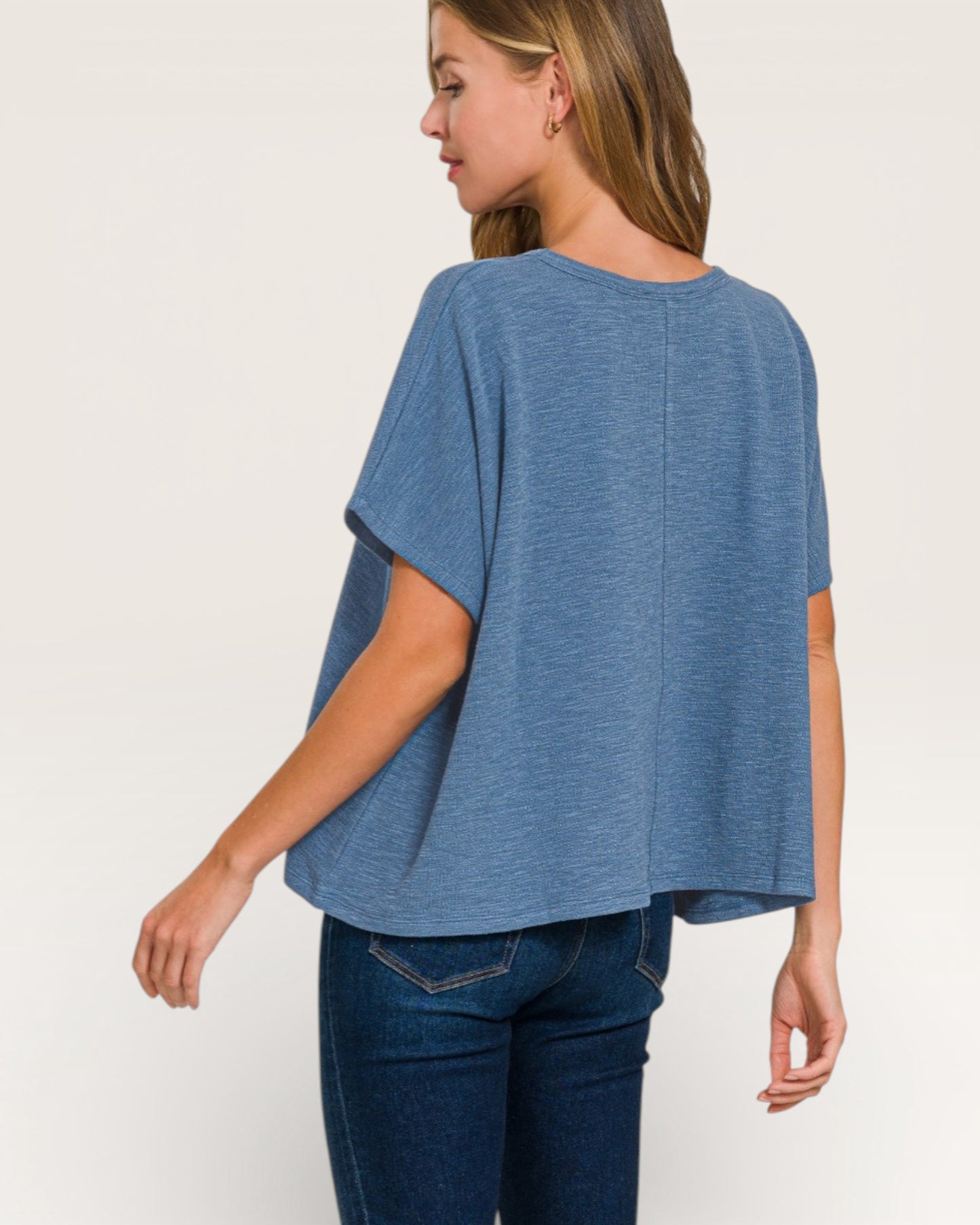 Woman wearing a blue oversized top and jeans on a white background