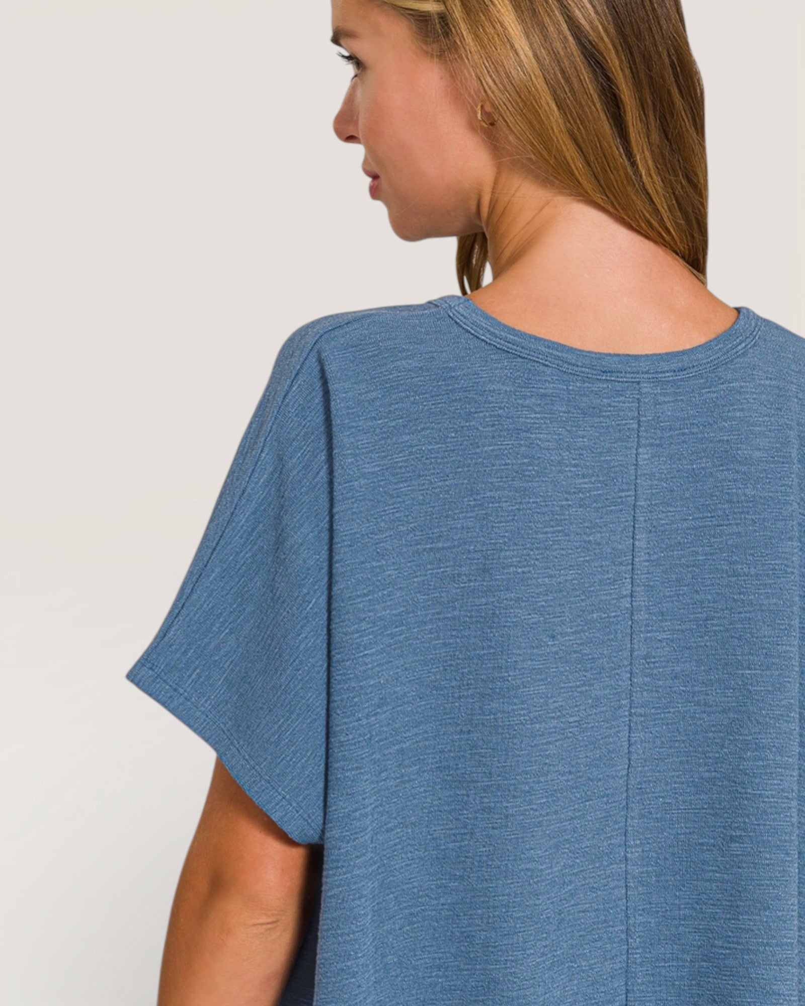 Woman wearing a blue t-shirt against a plain background
