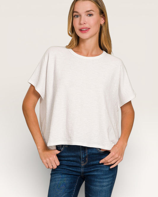 Woman wearing a white oversized t-shirt and blue jeans on a plain background