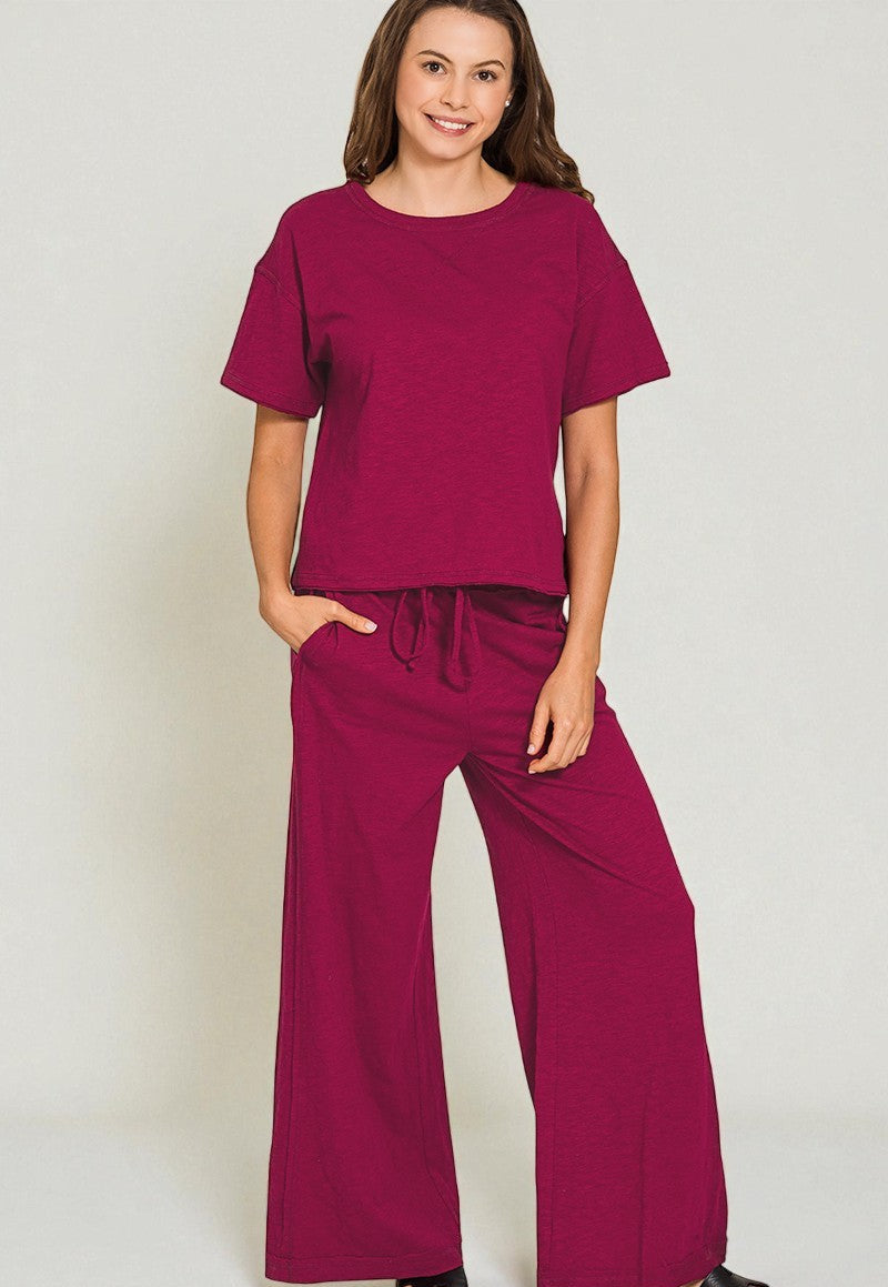 Woman wearing a matching maroon top and wide-leg pants against a plain background