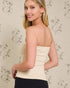 Woman wearing a beige strapless top against a floral wallpaper background