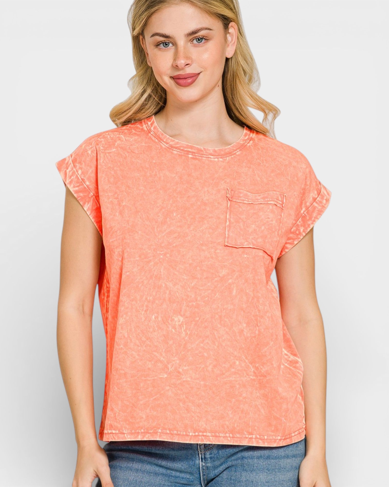Woman wearing a coral t-shirt with a pocket on a plain background