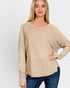 Woman wearing a beige long-sleeve top against a white background
