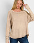 Woman wearing a beige long-sleeve top against a plain background