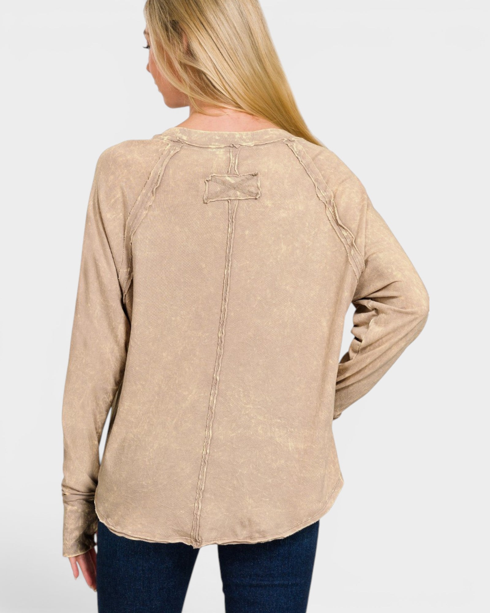Woman wearing a beige long-sleeve shirt with a logo on the back against a white background