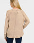 Woman wearing a beige long-sleeve shirt with a logo on the back against a white background
