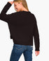 A woman wearing a black ribbed knit sweater and blue jeans, shown from the back against a plain white background.