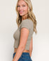 Woman wearing a beige crop top and blue jeans on a plain background