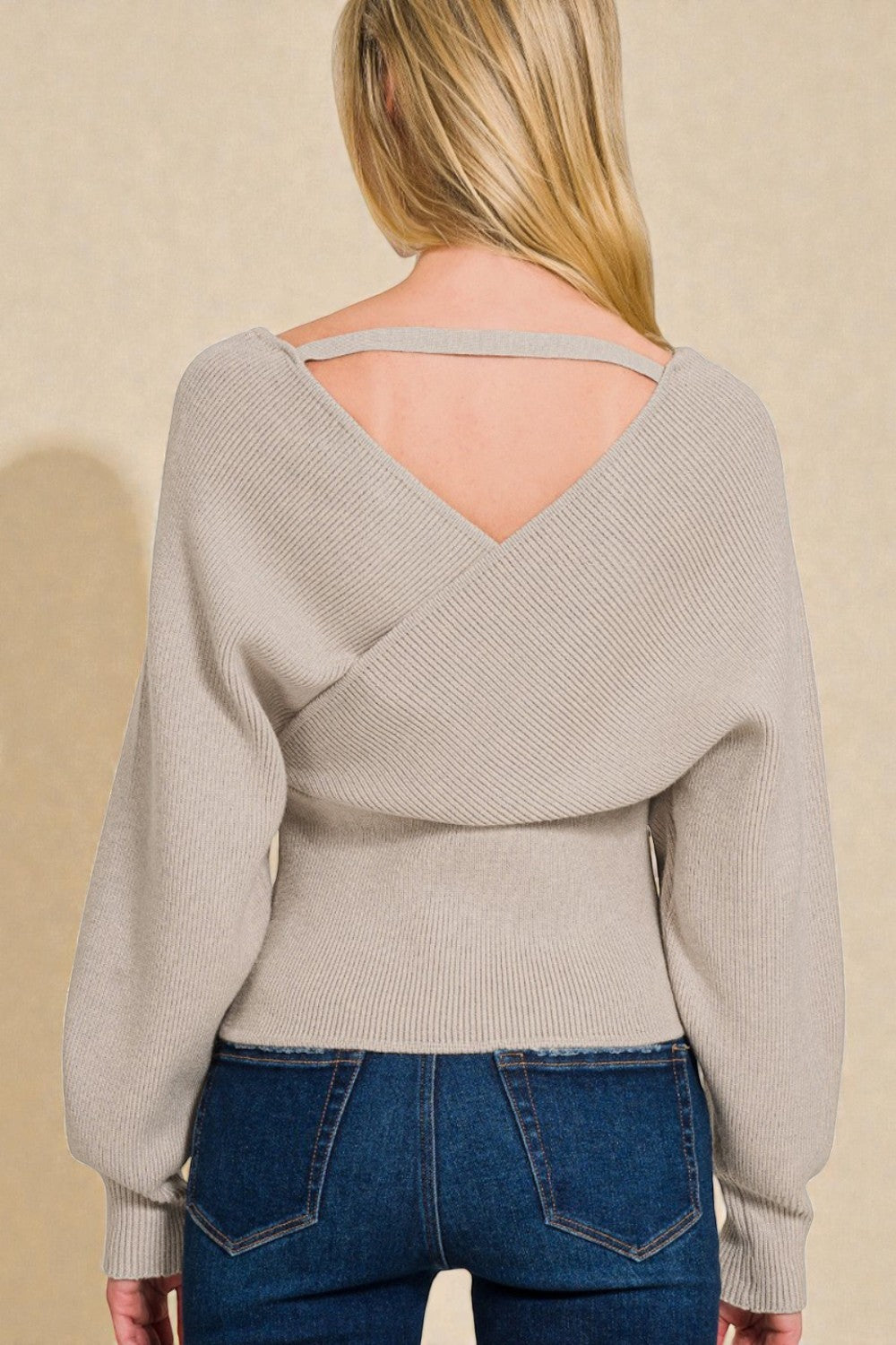 Beige sweater with open back worn by a person against a beige background
