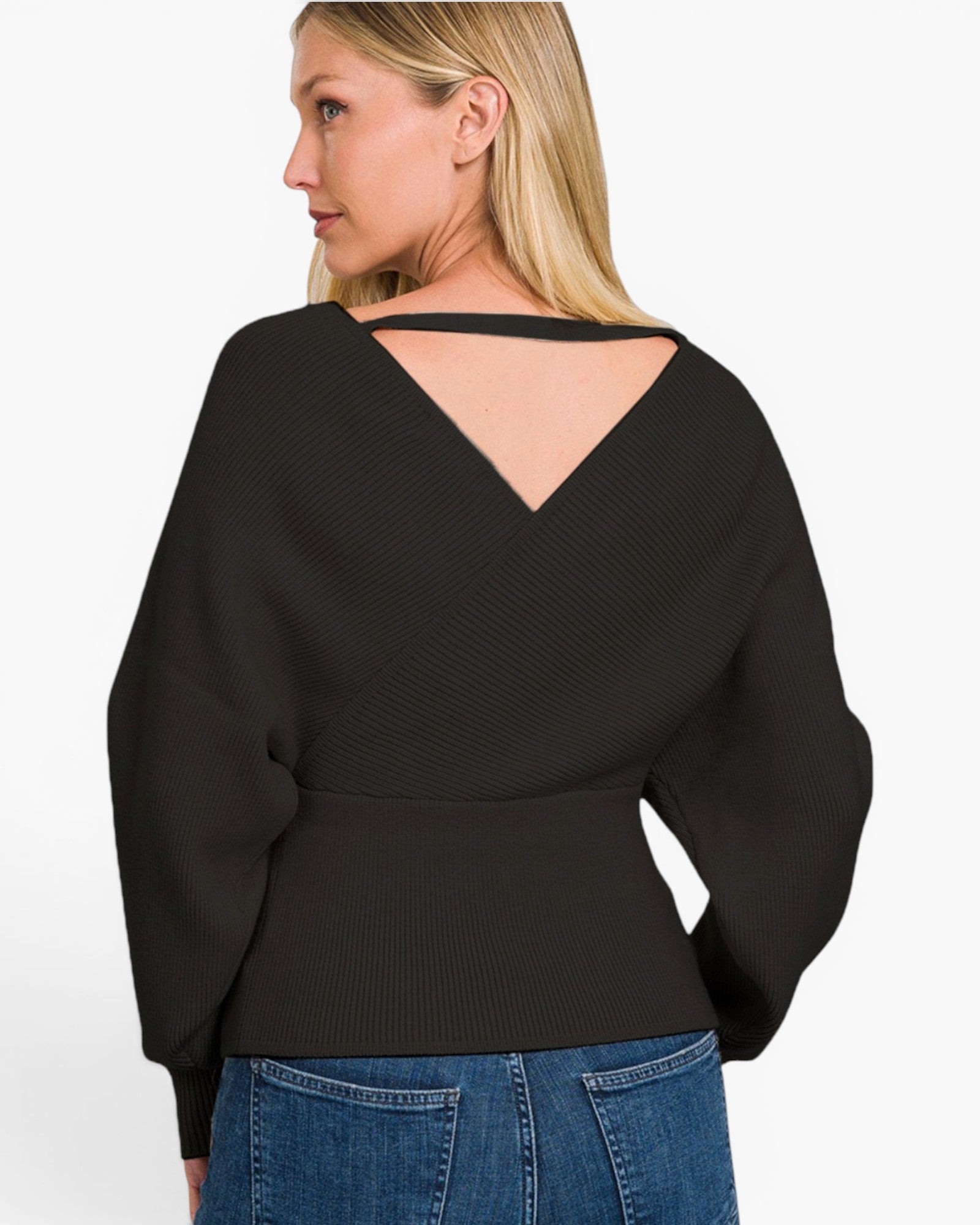 A woman shown from the back wearing a black long-sleeve knit top with a V-shaped open back and blue jeans, against a plain light background.
