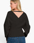 A woman shown from the back wearing a black long-sleeve knit top with a V-shaped open back and blue jeans, against a plain light background.