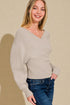 Woman wearing a beige sweater and blue jeans against a beige background
