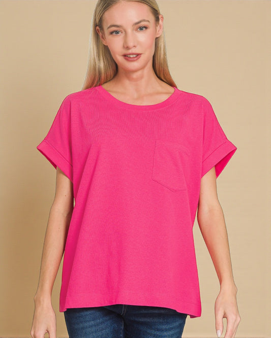 Woman wearing a bright pink t-shirt with a pocket on a beige background