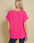 Person wearing a bright pink t-shirt against a beige background