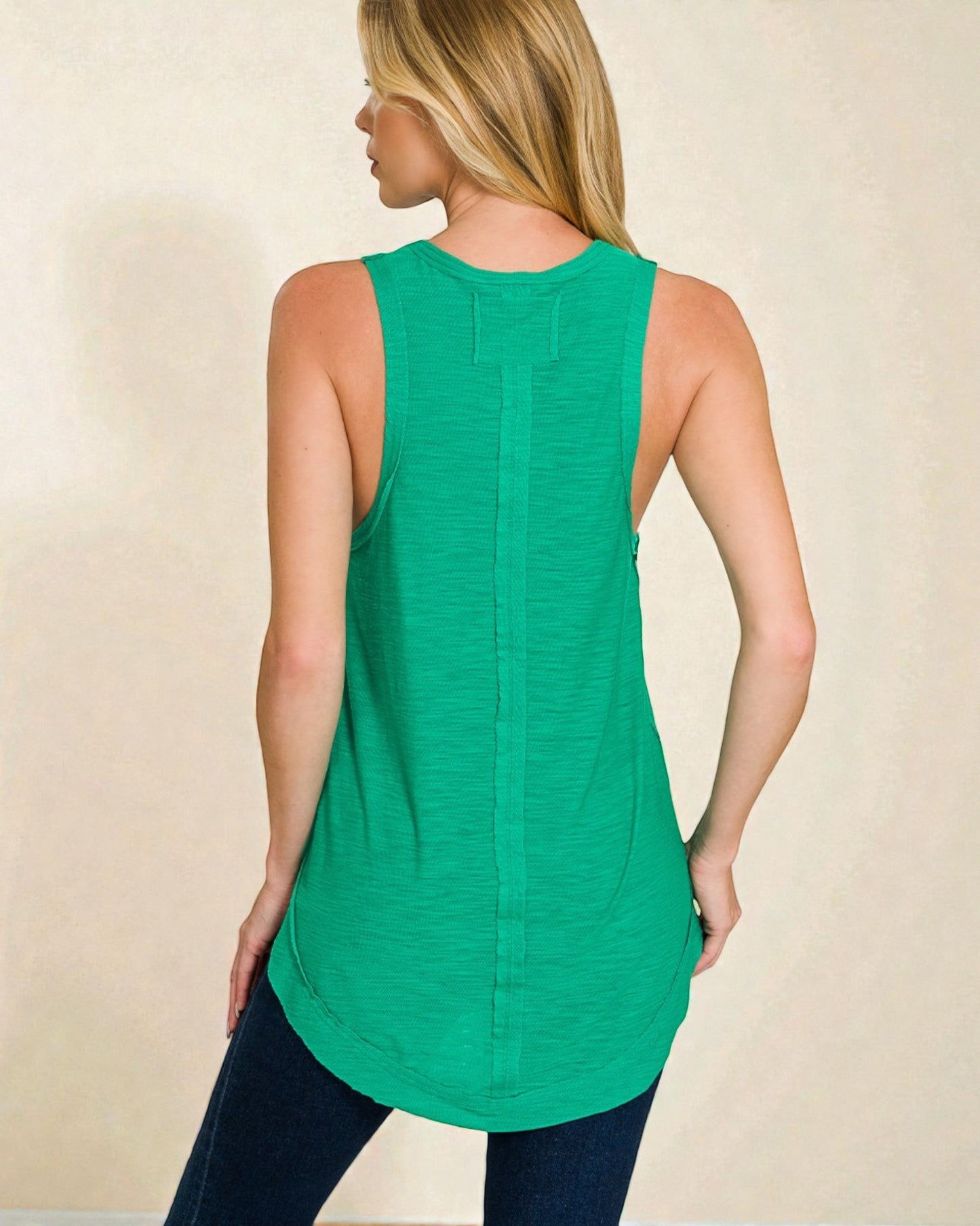 Woman wearing a green sleeveless top against a beige background