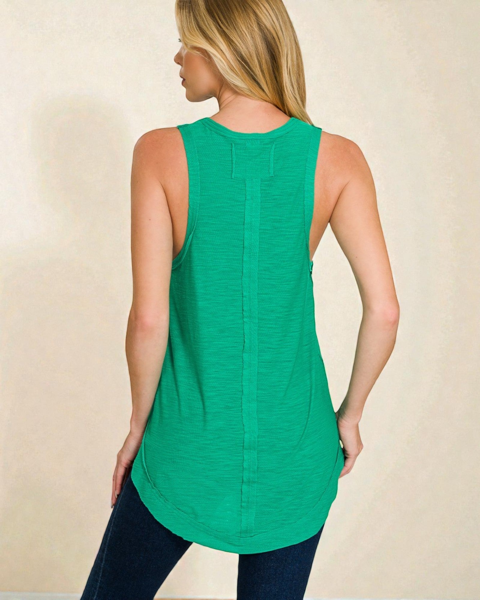 Woman wearing a green sleeveless top against a beige background