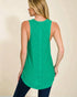 Woman wearing a green sleeveless top against a beige background