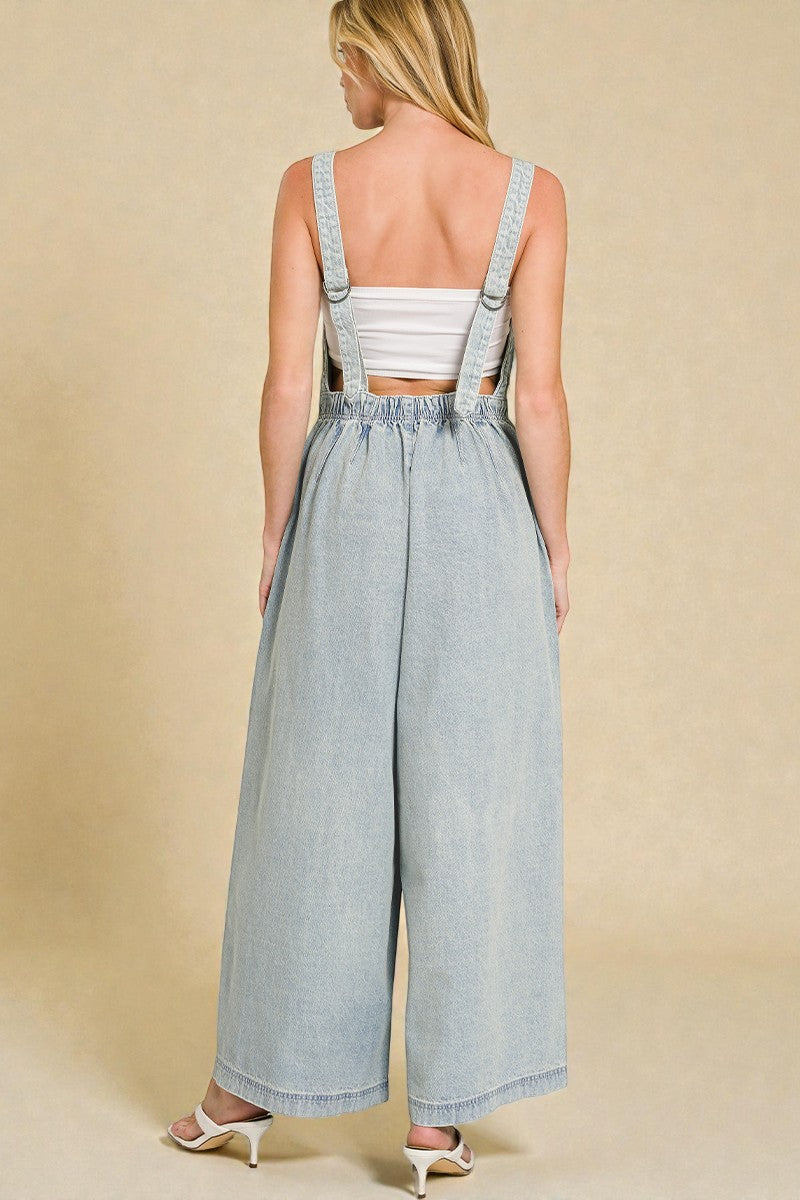 Woman wearing a light blue denim jumpsuit with a beige background